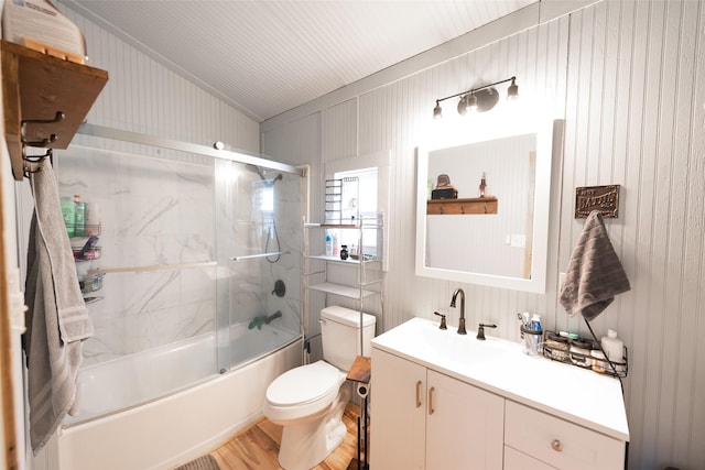 bathroom with combined bath / shower with glass door, toilet, vanity, and wood finished floors