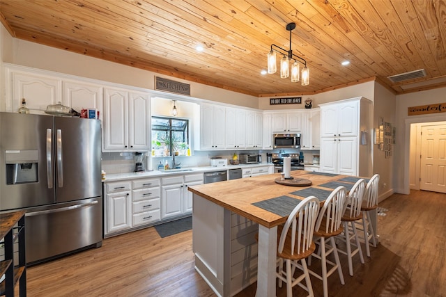 kitchen with visible vents, backsplash, appliances with stainless steel finishes, white cabinets, and wood counters