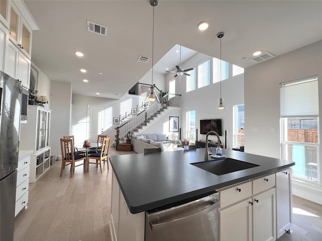 kitchen with visible vents, a sink, appliances with stainless steel finishes, dark countertops, and light wood-type flooring