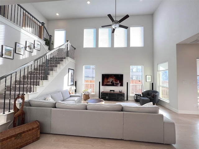 living room featuring stairway, a ceiling fan, light wood-style floors, and baseboards