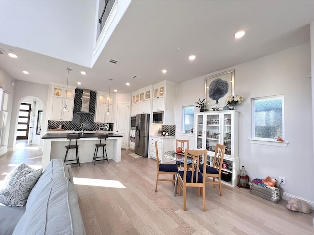 dining space with arched walkways, visible vents, recessed lighting, and light wood finished floors