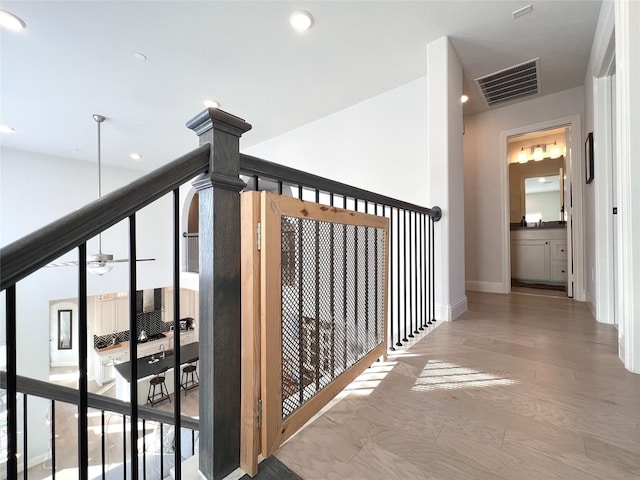 corridor with wood finished floors, visible vents, baseboards, recessed lighting, and an upstairs landing