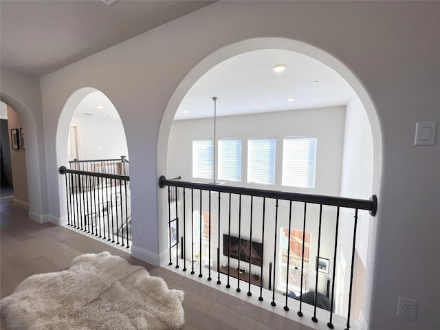 hall with recessed lighting, baseboards, arched walkways, and wood finished floors