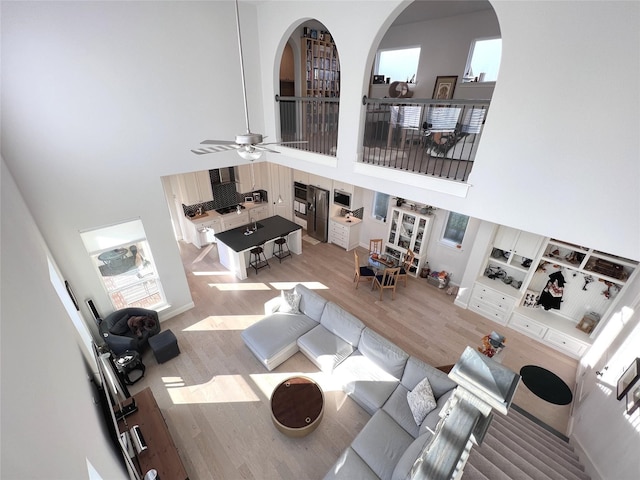 living room featuring wood finished floors, a towering ceiling, and ceiling fan