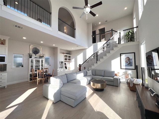 living area with a wealth of natural light, visible vents, wood finished floors, and stairs