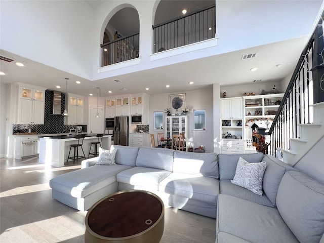 living room with stairs, recessed lighting, light wood-style floors, and visible vents