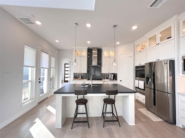 kitchen with stainless steel appliances, backsplash, visible vents, and wall chimney range hood