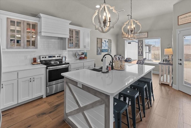 kitchen with custom exhaust hood, a kitchen breakfast bar, a sink, stainless steel electric range, and a notable chandelier