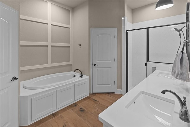 full bathroom featuring a bath, wood finished floors, a shower stall, and a sink