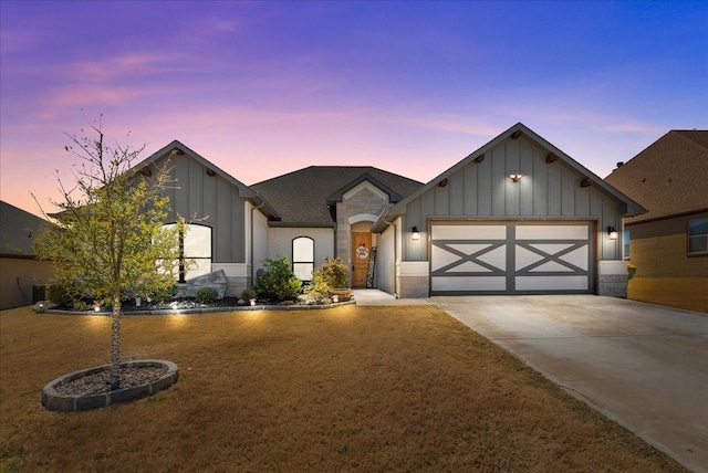view of front of home with concrete driveway, board and batten siding, a lawn, and a garage
