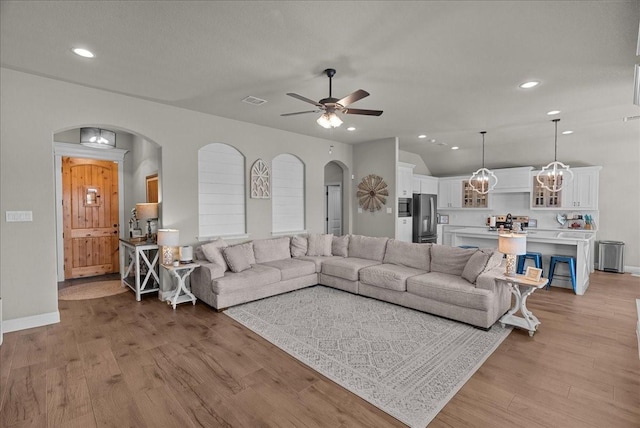 living area with recessed lighting, ceiling fan, arched walkways, and light wood-style flooring