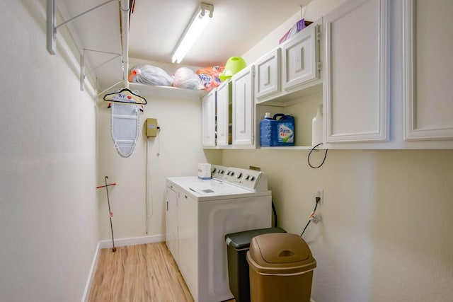 clothes washing area featuring cabinet space, washer and dryer, light wood finished floors, and baseboards