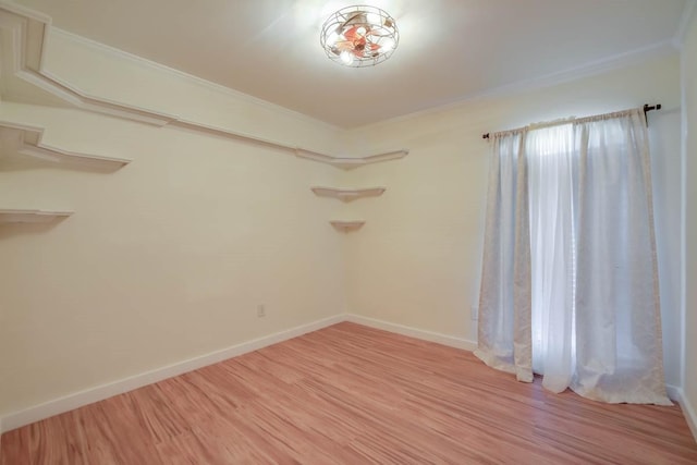 spare room featuring baseboards, light wood finished floors, and ornamental molding