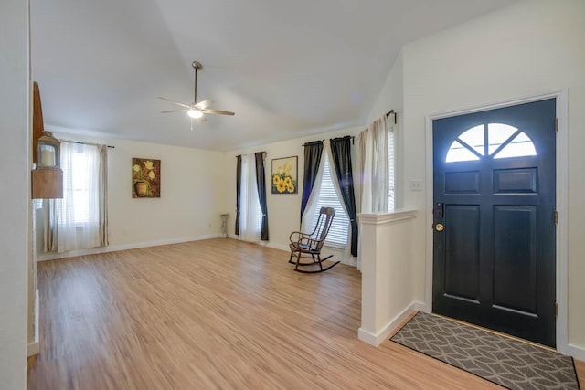 foyer entrance with lofted ceiling, light wood-style floors, baseboards, and ceiling fan