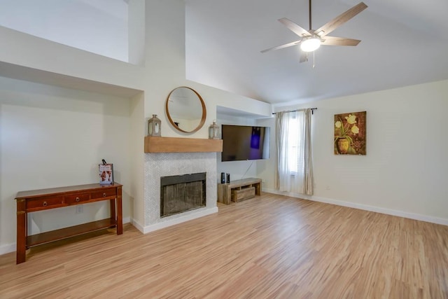 living room with light wood-style flooring, baseboards, ceiling fan, and a tiled fireplace