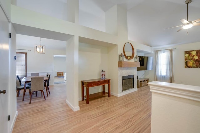 living room featuring a ceiling fan, light wood-style flooring, a fireplace, and baseboards