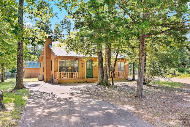 736 Wildwood Trl, Holly Lake Ranch, TX 75765 - rustic home with covered porch, driveway, and a chimney