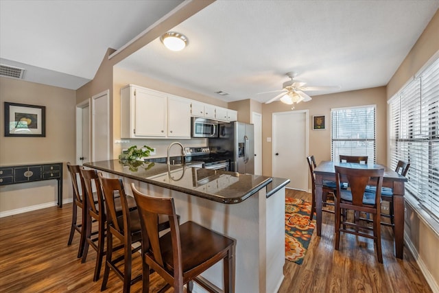 736 Wildwood Trl, Holly Lake Ranch, TX 75765 - kitchen with appliances with stainless steel finishes, dark wood-type flooring, a peninsula, white cabinetry, and a ceiling fan