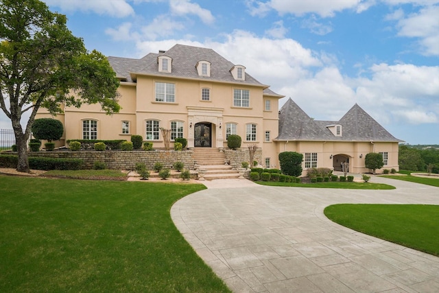 french country inspired facade featuring a front yard, curved driveway, and stucco siding