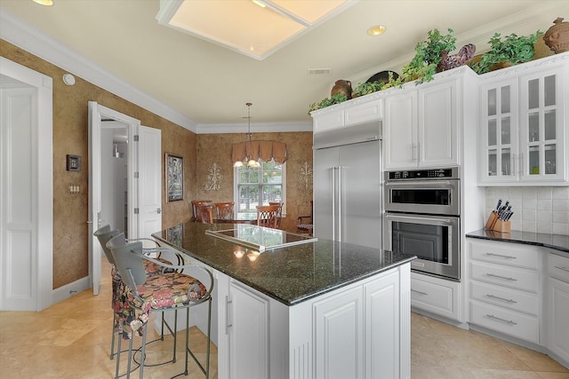 kitchen with white cabinetry, ornamental molding, appliances with stainless steel finishes, and a center island