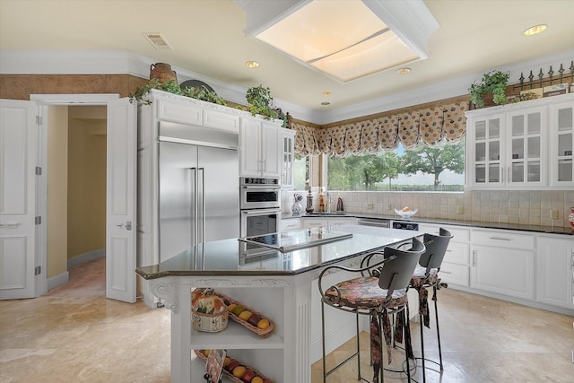 kitchen featuring a kitchen bar, open shelves, backsplash, appliances with stainless steel finishes, and glass insert cabinets