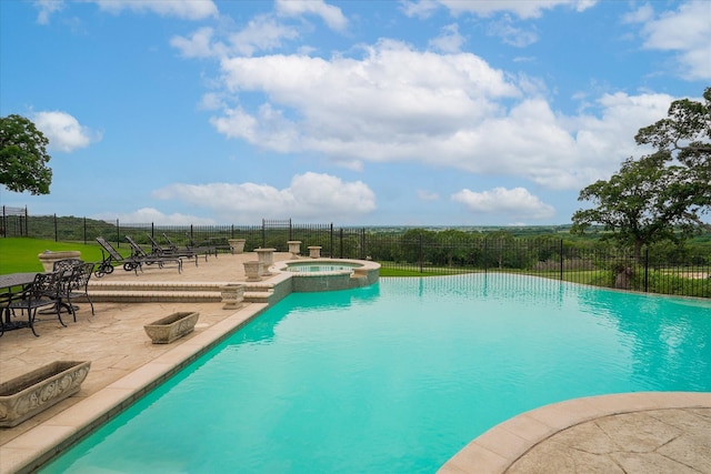 view of pool with a pool with connected hot tub, a patio, and fence