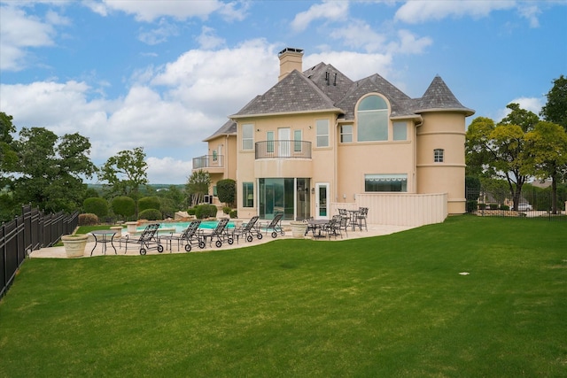 rear view of house with a fenced in pool, fence, a yard, a balcony, and a patio area