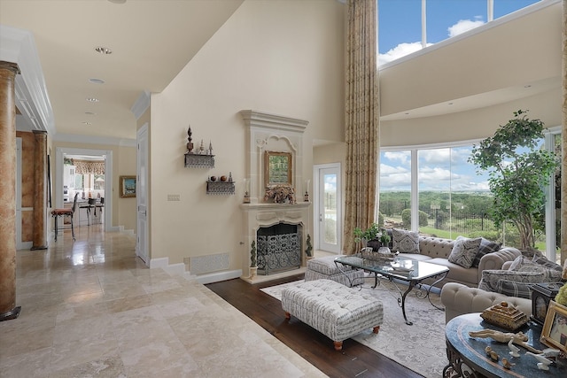 living room featuring decorative columns, a healthy amount of sunlight, visible vents, and a fireplace with raised hearth