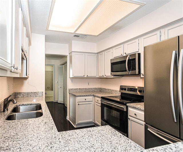 8600 Coppertowne Ln Unit 303C, Dallas, TX 75243 - kitchen featuring stainless steel appliances, a sink, light stone countertops, and dark wood-style floors