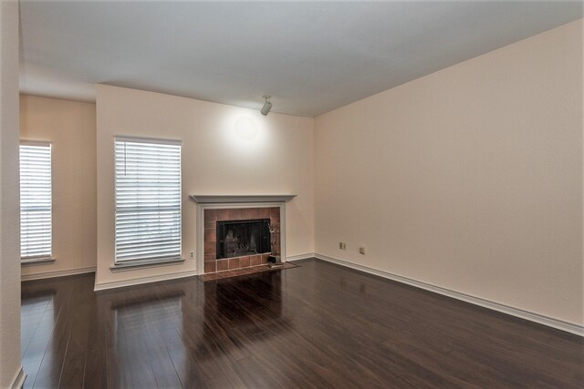 8600 Coppertowne Ln Unit 303C, Dallas, TX 75243 - unfurnished living room featuring dark wood-style flooring, a fireplace, and baseboards