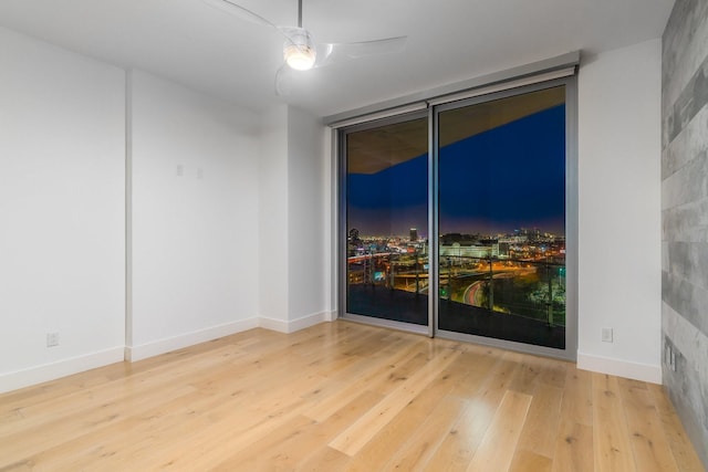 spare room with baseboards, floor to ceiling windows, a ceiling fan, and hardwood / wood-style floors