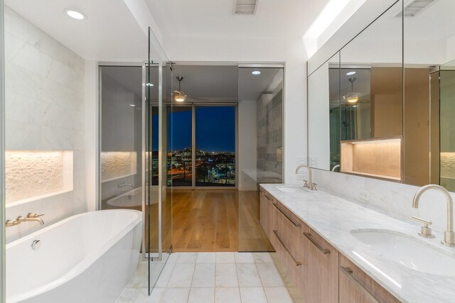 full bath with visible vents, a sink, a soaking tub, and double vanity