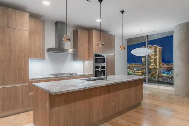 kitchen featuring modern cabinets, light wood-style flooring, wall chimney exhaust hood, and appliances with stainless steel finishes