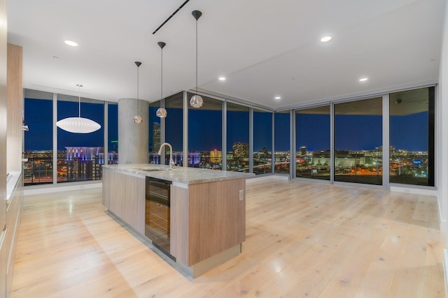 kitchen featuring expansive windows, wine cooler, a sink, modern cabinets, and light wood-style flooring