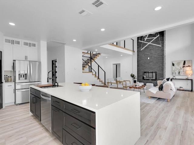 310 Harborview Dr, Rockwall, TX 75032 - kitchen with stainless steel appliances, a sink, white cabinetry, a center island with sink, and light wood-style floors