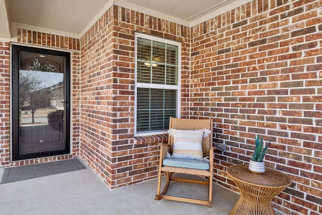 view of exterior entry with brick siding and covered porch