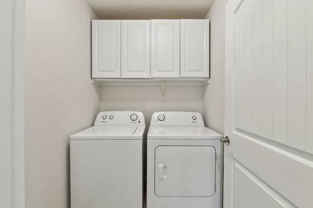 washroom featuring cabinet space and washer and clothes dryer