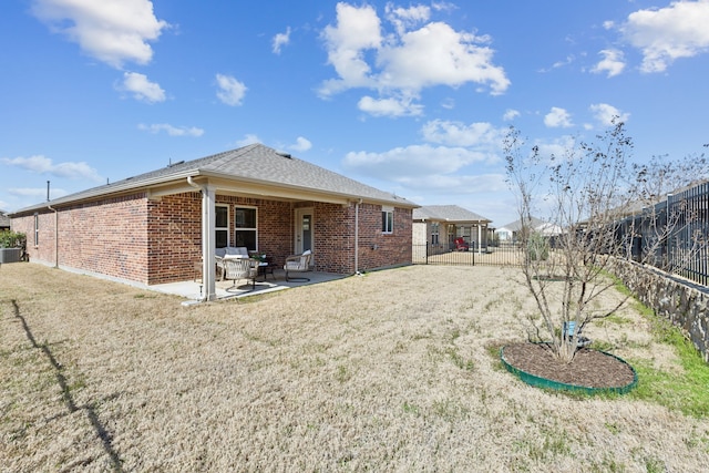 back of property featuring brick siding, a patio area, a lawn, and a fenced backyard