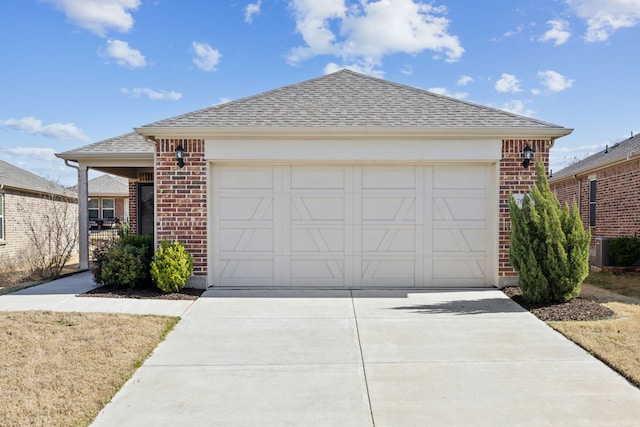single story home with central AC unit, a shingled roof, concrete driveway, brick siding, and a garage