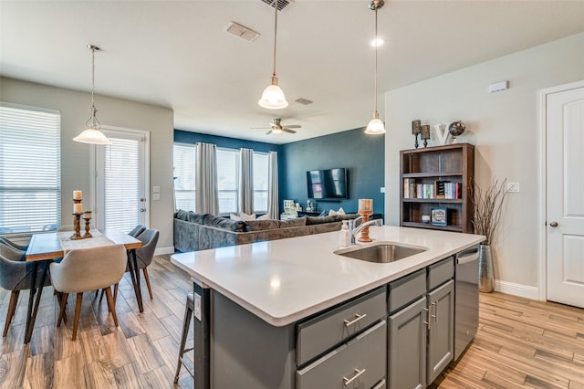 kitchen with dishwasher, light wood-type flooring, light countertops, gray cabinets, and a sink