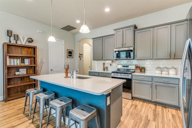 kitchen with visible vents, arched walkways, gray cabinets, stainless steel appliances, and backsplash