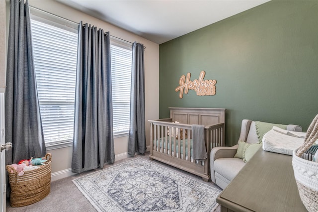 carpeted bedroom with a crib and baseboards