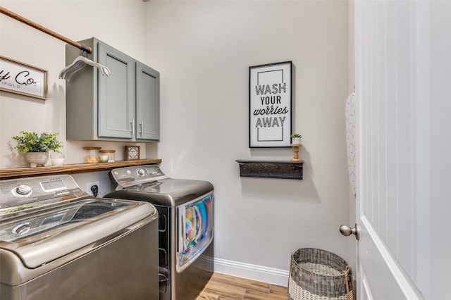 laundry room featuring cabinet space, baseboards, light wood finished floors, and washer and clothes dryer