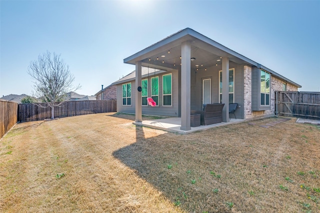 rear view of property with a lawn, a patio, and a fenced backyard