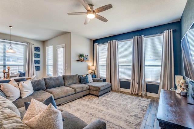 living area with ceiling fan, baseboards, and wood finished floors