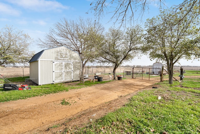 view of yard featuring a storage shed, fence, an outdoor structure, and a gate