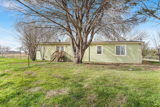 rear view of house featuring a yard and fence