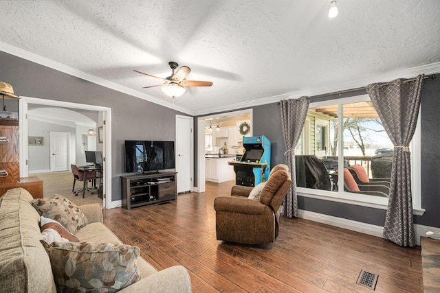 living area featuring a textured ceiling, wood finished floors, arched walkways, and ceiling fan