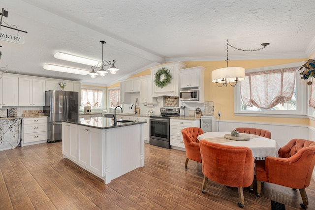 kitchen with lofted ceiling with beams, a sink, dark wood-style floors, stainless steel appliances, and an inviting chandelier