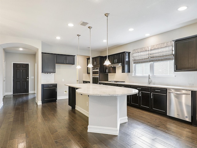 1722 Port Royal Ln, Frisco, TX 75036 - kitchen featuring stainless steel appliances, arched walkways, a kitchen island, a sink, and under cabinet range hood